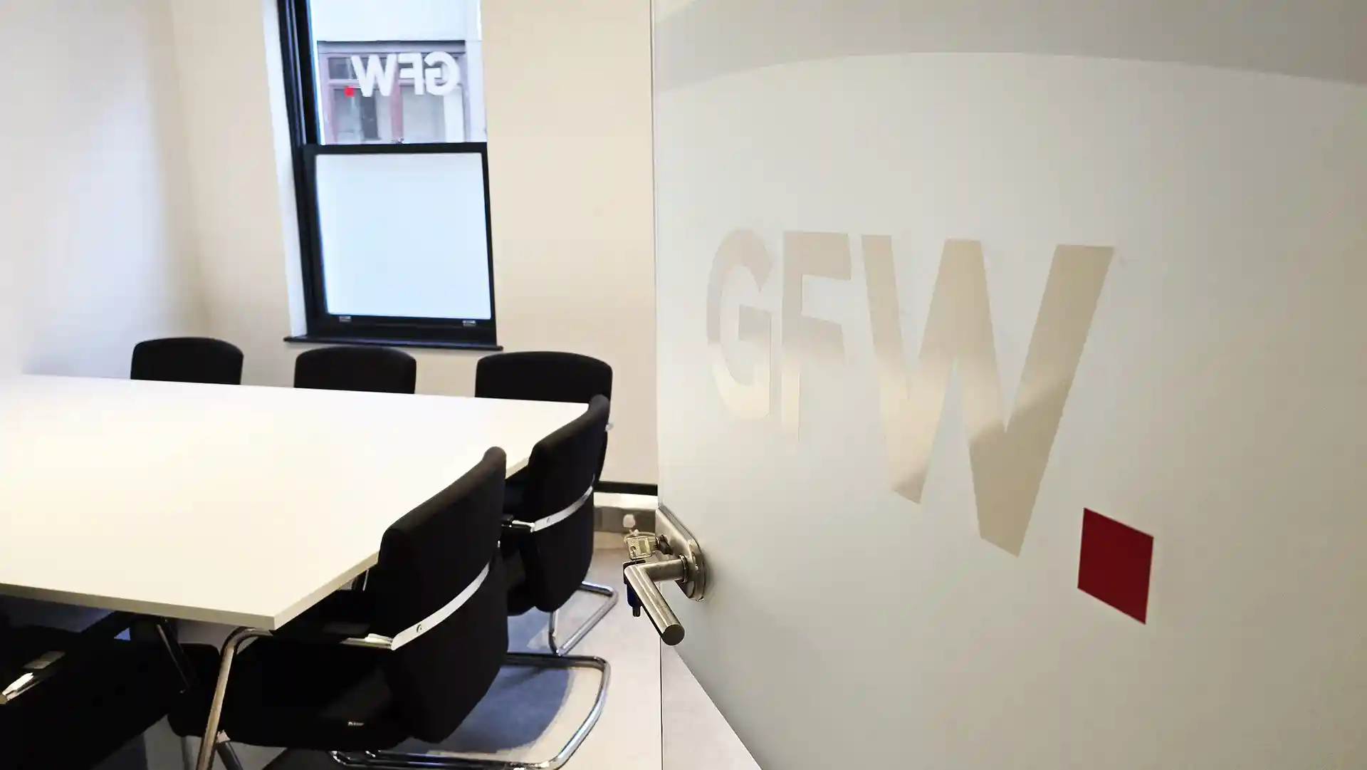 Glass door with GFW logo applied ajar into a meeting room