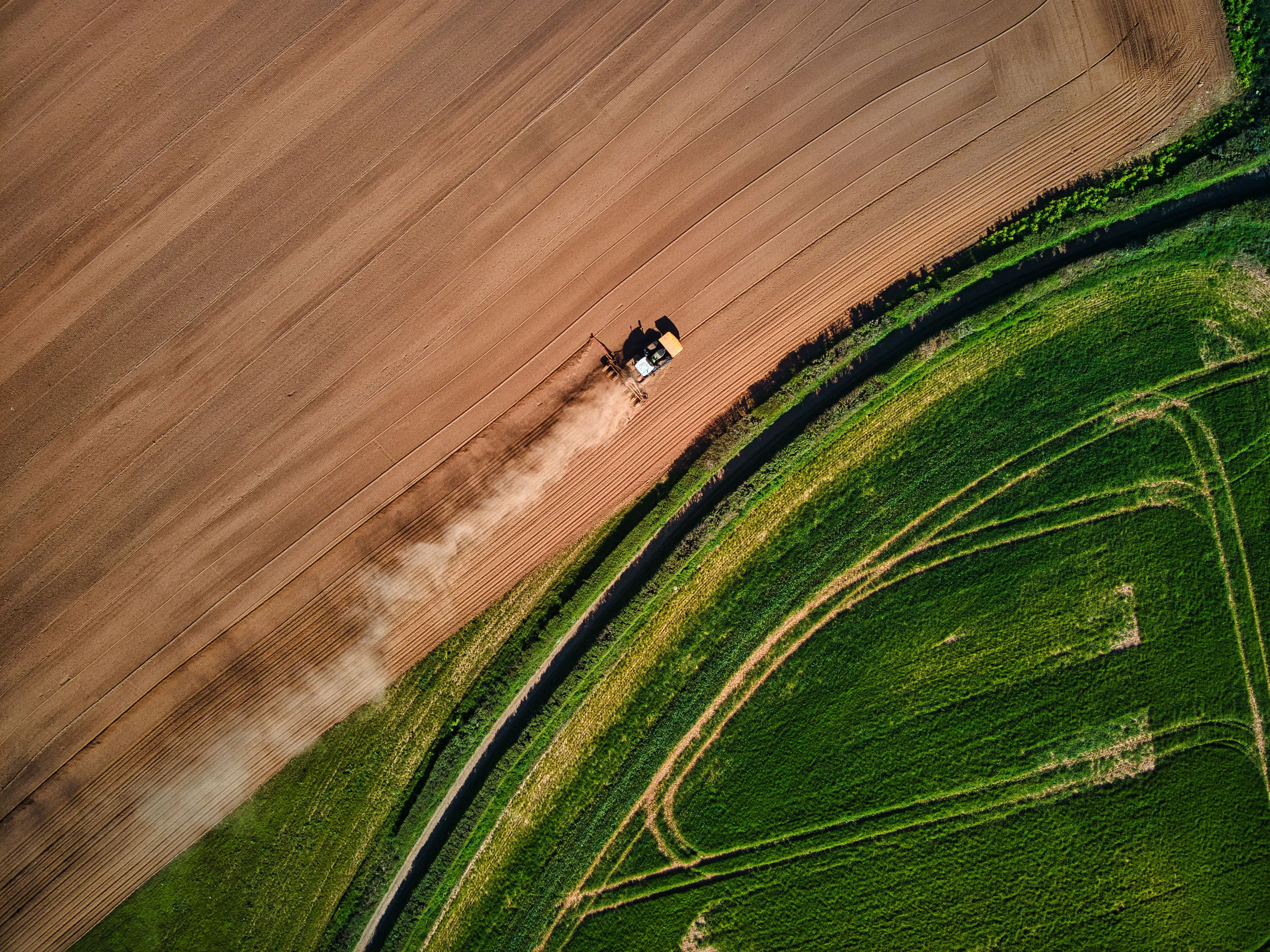 field and farm machinery with green and orange hues